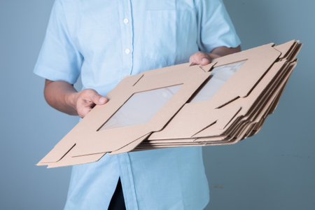 Delivery man holding cardboard boxes on a blue background, delivery service concept.
