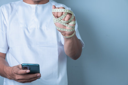 Healthcare and medicine concept. Doctor holding measuring tape and smartphone.の写真素材