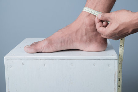 Close up of man measuring his foot with tape measure on white box