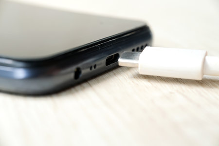 Smartphone and USB cable on wooden table. Selective focus.の写真素材