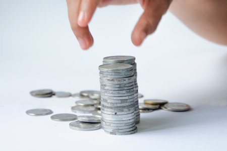 Hand put coin stack on white background, save money for prepare in the future.の写真素材