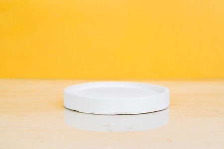 Empty white circle podium on wood table and yellow background, product displayの写真素材