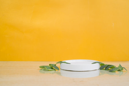 Cosmetic cream with eucalyptus leaves on yellow backgroundの写真素材