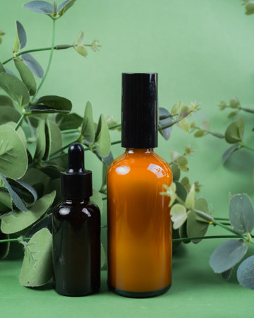 Bottle of essential oil on green background with eucalyptus leavesの写真素材