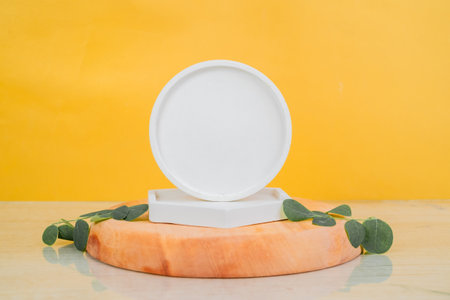 White round cosmetic container with eucalyptus leaves on orange backgroundの写真素材