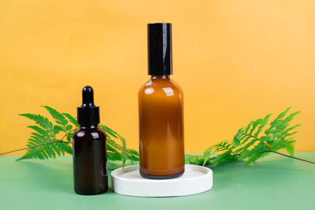 Mockup of brown glass dropper bottles with green leaves on yellow backgroundの写真素材