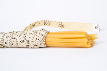 Pasta and measuring tape on a white background. Diet concept.の写真素材
