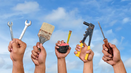 Hands holding construction tools on blue sky background. Construction concept.の写真素材