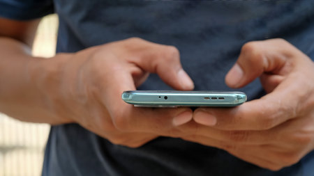 Close-up of Asian male hand holding mobile phone, waiting or missing important call, wasting time online, addicted to internet conceptの写真素材
