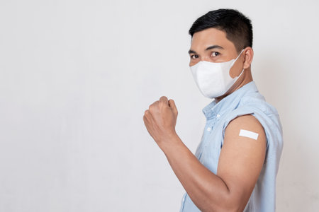Vaccinated Asian adult man showing adhesive plaster bandage on his arm after anti-virus injection. I've Got the Vaccineの写真素材