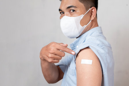 Vaccinated Asian adult man showing adhesive plaster bandage on his arm after anti-virus injection. I've Got the Vaccineの写真素材