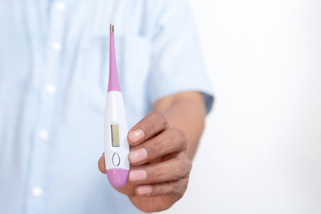 Doctor's hand holding a digital thermometer.