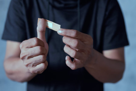Man placing bandage or adhesive plaster on his thumb finger. plaster on the woundの写真素材