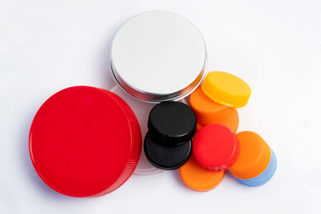 Pile of plastic bottle caps and jars isolated on white. Recyclable trash