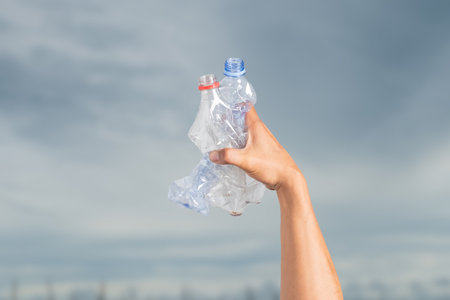 Crumpled waste plastic bottles in male hands. Recyclable trashの写真素材