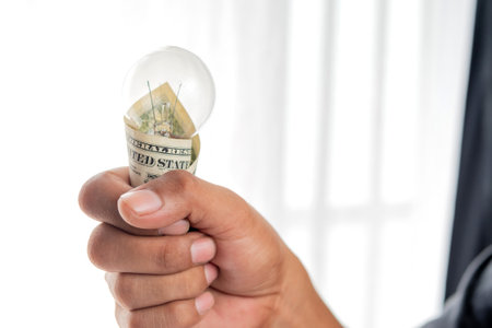Hands holding light bulbs and banknotes, Electricity prices rise sharply. Electricity price increase conceptの写真素材