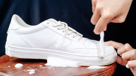 Woman cleaning white leather shoes with cleaning foam. The concept of caring for leather footwearの写真素材