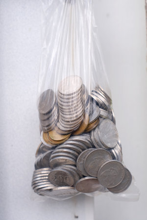 Coins in plastic bag on white wall background. Saving money concept.