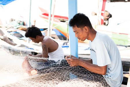 Lampung, Indonesia, June 18 2023: The fisherman is repairing the fishing net on the boat in the village, Indonesiaのeditorial素材