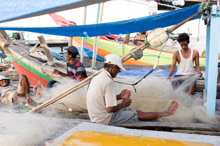 Lampung, Indonesia, June 18 2023: The fisherman is repairing the fishing net on the boat in the village, Indonesiaのeditorial素材