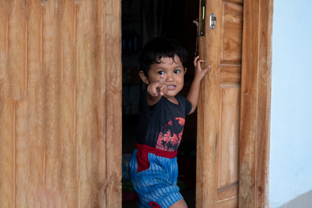 Boy standing in doorway with hand pointing to cameraの写真素材