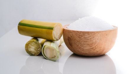 Close up of sugarcane and wooden bowl with sugar cubes on white backgroundの写真素材
