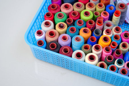 Colorful sewing threads in a blue plastic box on a white background