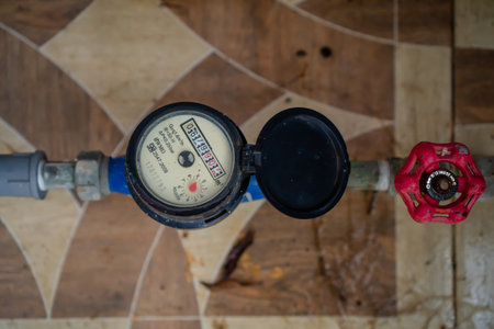 Closeup Of Water Meter With Open Lid And Red Valve On Wooden Floorの写真素材