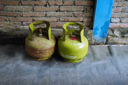 Two Rusty Green Gas Cylinders Against Brick Wallの写真素材