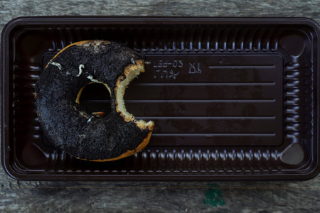 Partially Eaten Black Sesame Donut in Brown Plastic Trayの写真素材