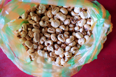 Roasted peanuts in a plastic bag on a red tablecloth.の写真素材