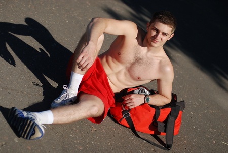 The sportsman after warm-up sits with a bagの写真素材