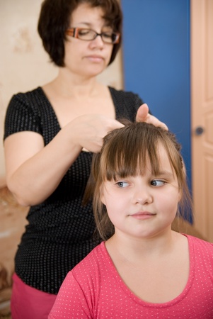 Mum does a hairdress of the daughter,in a roomの写真素材
