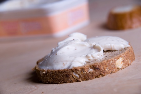 Piece of bread with a cheese cream on a wooden tableの写真素材