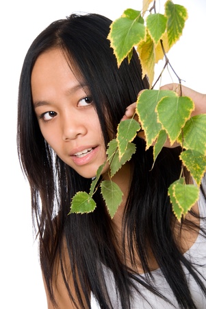 The young Vietnamese girl looks out because of a birch branch,isolated on white backgroundの写真素材