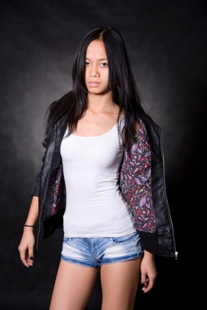 Portrait of Asian girl in a leather jacket on a black backgroundの写真素材