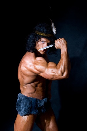 Strong athletic man with a knife on a black backgroundの写真素材