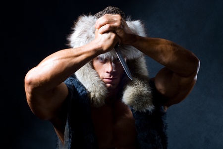 strong athletic man with a knife on a black backgroundの写真素材
