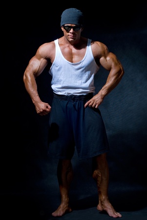 strong athletic man in dark glasses on a black backgroundの写真素材