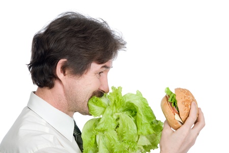 Man eats salad and looks at hamburger. Isolated on white backgroundの写真素材