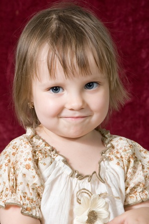 Portrait of the nice little girl on a red background in studioの写真素材