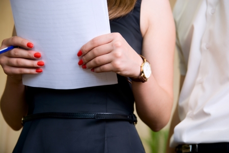 Woman holds document and man nearby in officeの写真素材