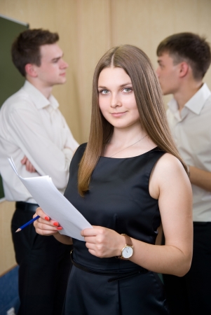 Happy business girl with documents and colleagues behindの写真素材