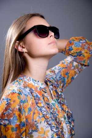 Portrait of a girl wearing sunglasses on a gray backgroundの写真素材