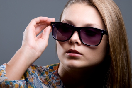 Close-up portrait of beautiful girl in sunglasses on a gray backgroundの写真素材