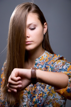 Lovely girl with long hair looks at the clockの写真素材