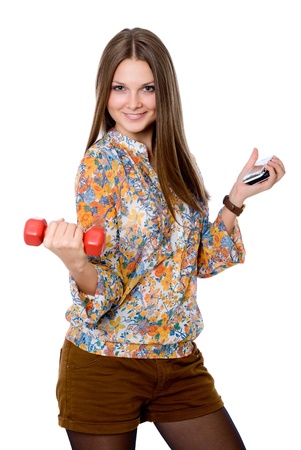 Portrait of a smiling young woman with dumbbell in one hand and cell phone in the other. isolated on white, studio shotの写真素材