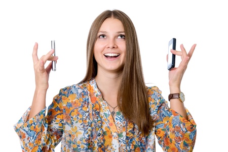 Beautiful girl with two mobile phones, isolated over white backgroundの写真素材