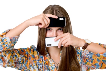 The girl with two mobile phones.Black and white phones. isolated over a white backgroundの写真素材