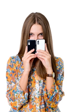 The girl with two mobile phones.Black and white phones. isolated over a white backgroundの写真素材